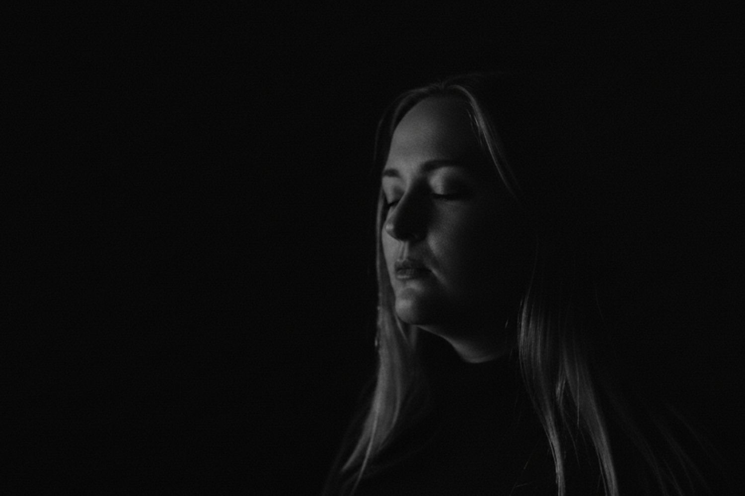 Constanzia Norström Portrait schwarzweiss Schwarz-Weiß-Porträt von Constanzia Norström mit geschlossenen Augen vor dunklem Hintergrund.
